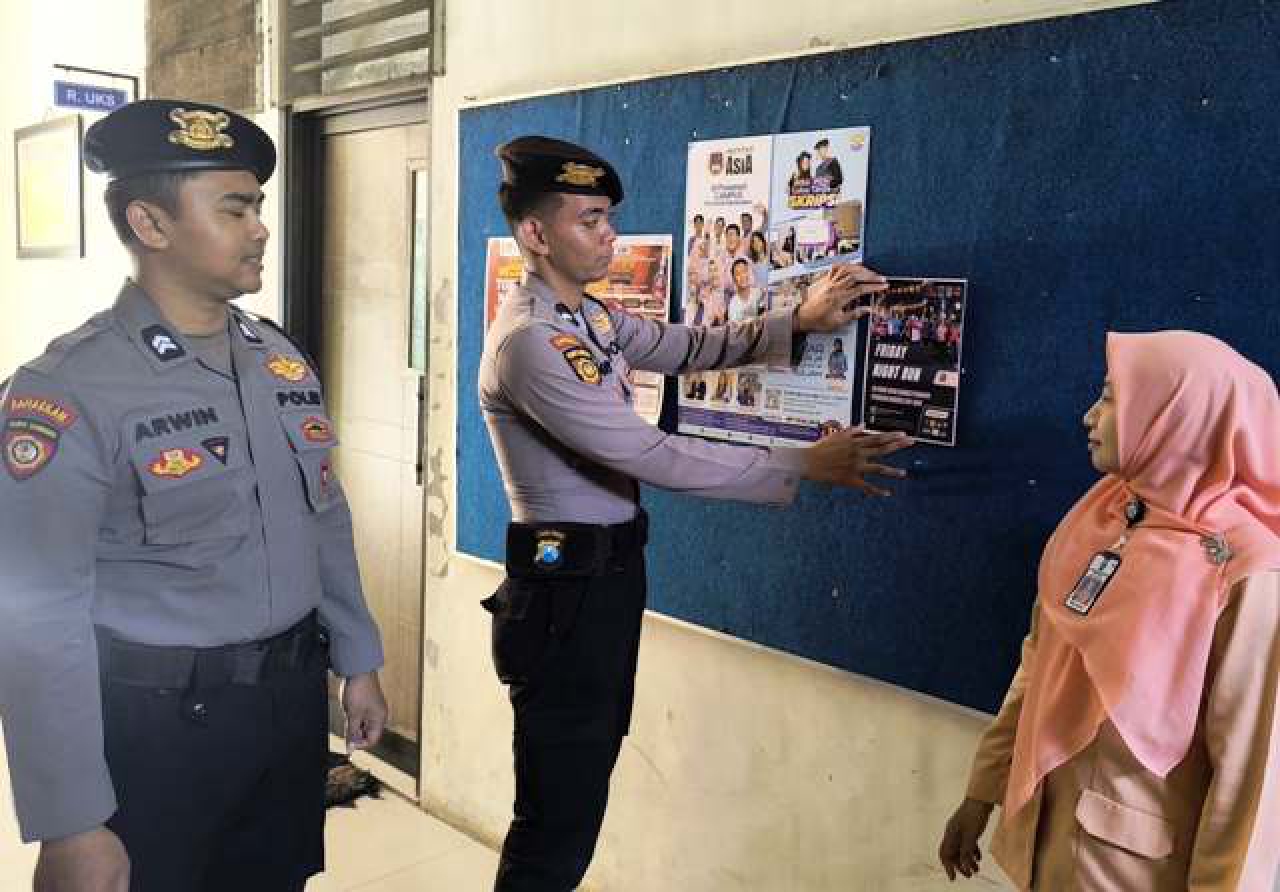 Anggota Polres Pasuruan Kota memasang pamflet Friday Nigh Run.