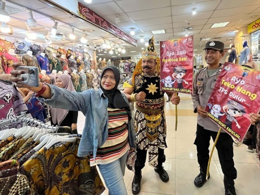 AIPDA Sandra anggota Bhabinkamtibmas Kapasan Polsek Simokerto menggunakan kostum Gatot Kaca berpose dengan warga saat sosialisasi Pemilu 2024, Selasa, (13/02/2024).